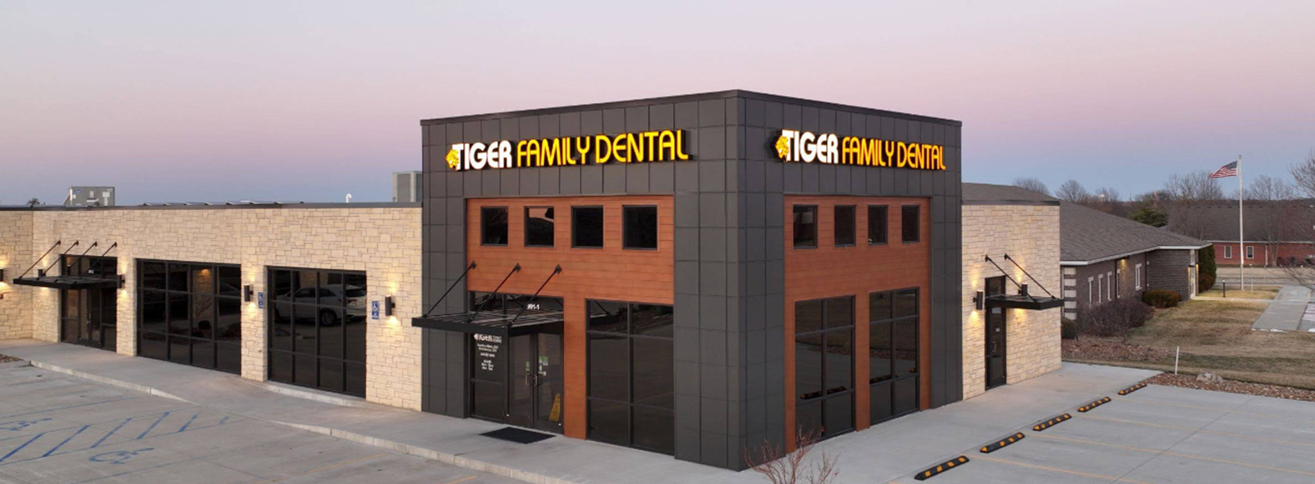 The image shows a modern building with a sign that reads Dentist on its facade, indicating it s a dental clinic.